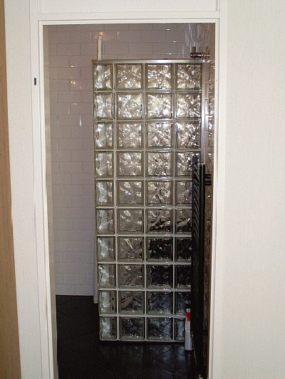 Doucheruimte met glasbouwstenen, waar leidingwerk en tegelwerk in één klus zijn gedaan.